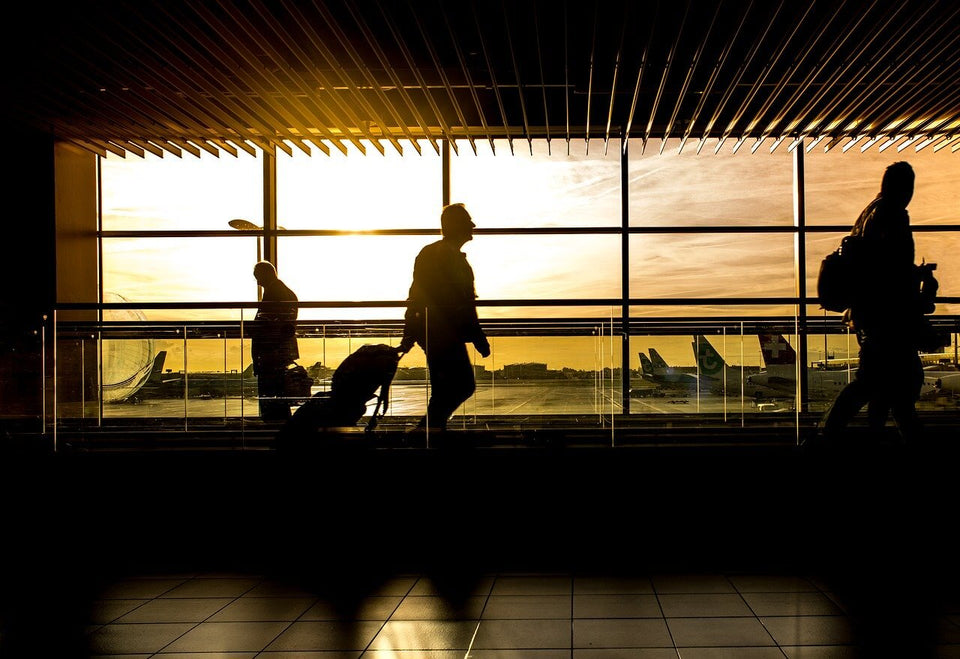 a silhouette of a man in an airport with a setting sun exposed behind him through airport windows